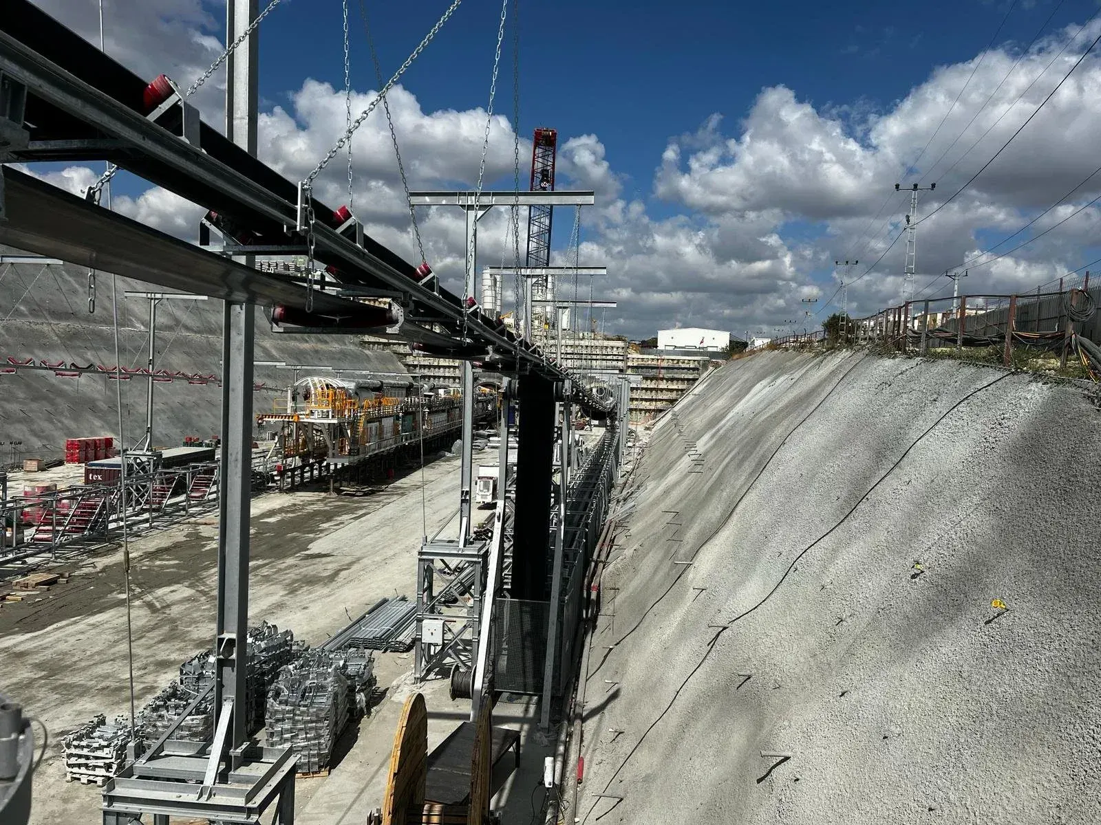Conveyor structure along an excavation slope with a locomotive on track