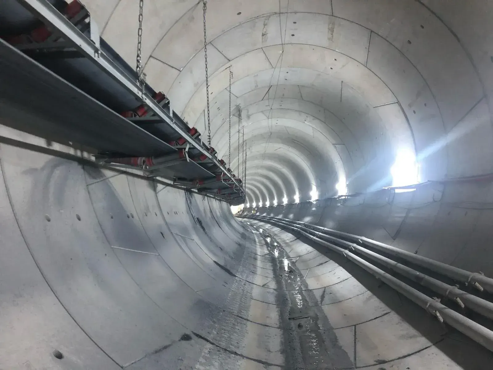 Belt conveyor running along a segment-lined tunnel
